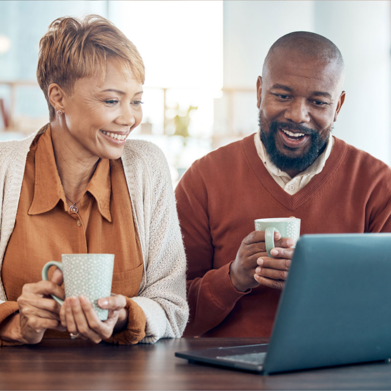 couple holding coffee and looking at computer